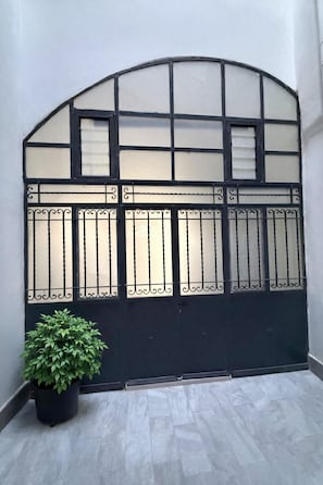 A black metal gate with decorative panels and a potted plant beside it. - Seafonia - Apartment in the Heart of Salerno (Salerno)