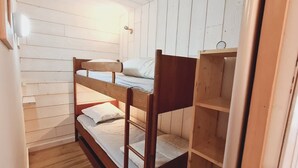 Habitación con literas, paredes de madera y una puerta.