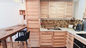 Una cocina compacta con muebles de madera, una mesa de comedor con sillas y una cafetera.