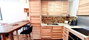 Cozinha compacta com armários de madeira, pia, fogão e um espaço de jantar com mesa e cadeiras.