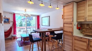 Una cocina con armarios de madera, una zona de asientos con taburetes de bar y un ventanal con vistas a un balcón.