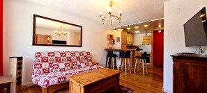A cozy living area with a patterned sofa, a wooden coffee table, and a dining area with bar stools. - Charming apartment for 6 people with a mountain view (Les Deux Alpes)