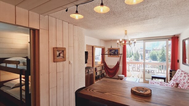 Una habitación con literas, una mesa de comedor, una hamaca y vistas al exterior.