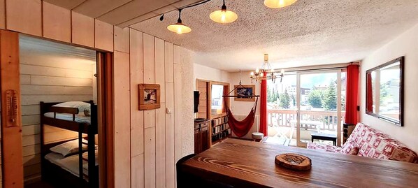 Een kamer met een stapelbed, een eettafel en uitzicht op de omgeving.