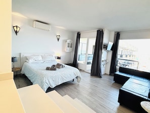 A hotel room with a bed, a sofa, a TV, and a balcony with curtains. - Benalmádena Mood Aloha Beachfront (Benalmádena)