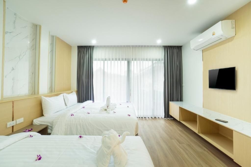 A hotel room with two beds, a TV, and an air conditioning unit.