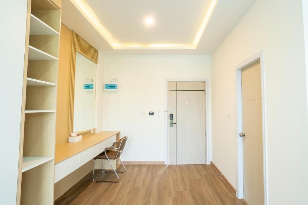 Une chambre d’hôtel avec un plancher en bois, une étagère intégrée, un bureau avec une chaise et une porte dotée d’une poignée.