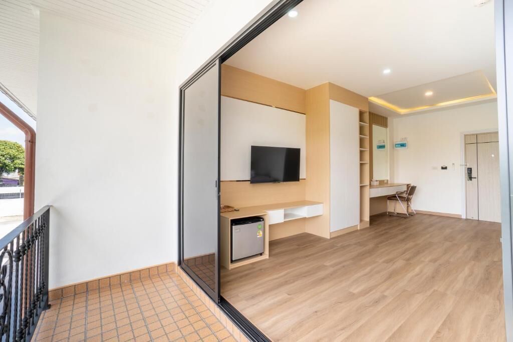 A modern interior with a flat-screen TV mounted on a wall, a small refrigerator, and a desk area.