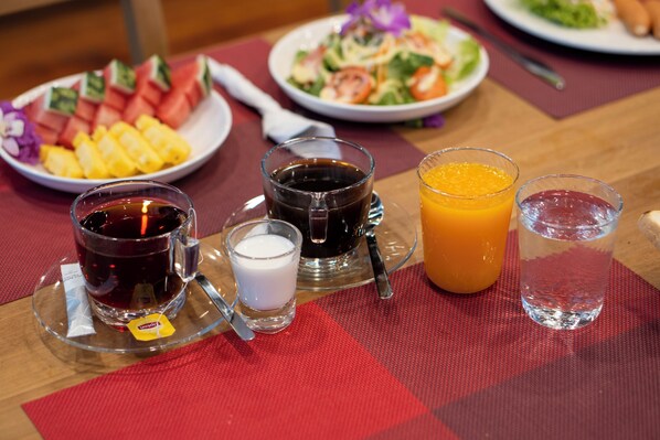 Une table mise pour le petit-déjeuner avec des assiettes de nourriture, une tasse de café, un verre de jus d’orange et un verre d’eau.