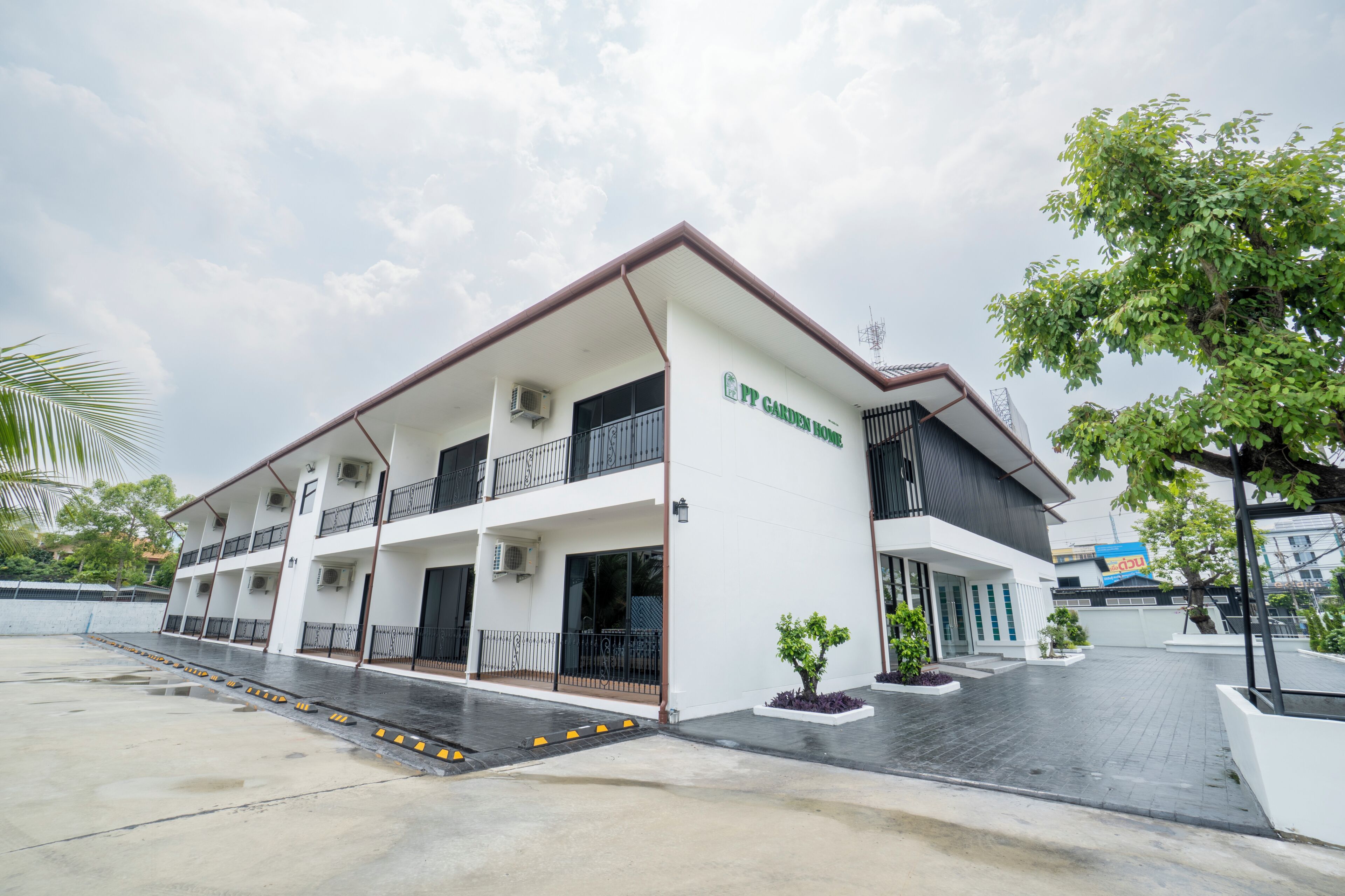 A multi-story building with a flat roof, air conditioning units, and a sign that reads 'PP Garden Home'.
