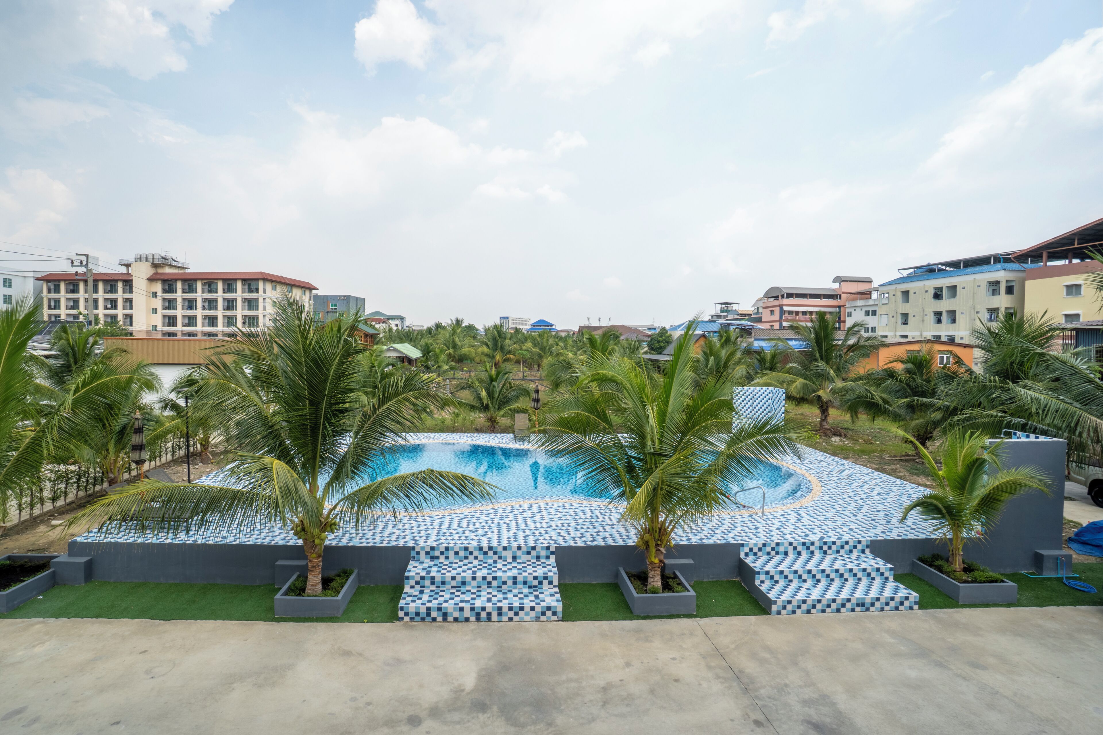 A swimming pool with palm trees and a view of surrounding buildings.