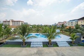 A swimming pool with palm trees and a view of surrounding buildings. - PP Garden Home (Bangkok)