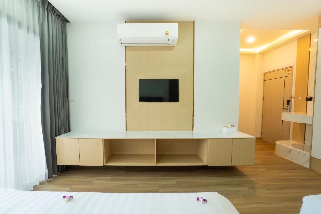 A hotel room with a built-in TV, a minibar, and a wooden floor.