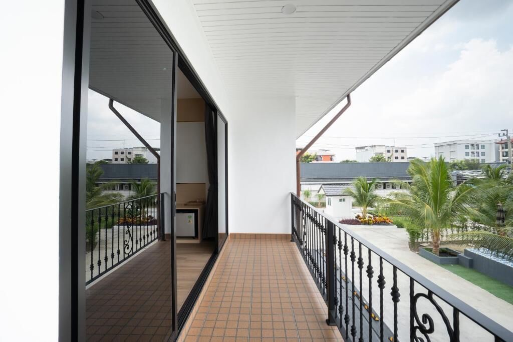 A balcony with a tiled floor, a black railing, and a view of buildings and palm trees.