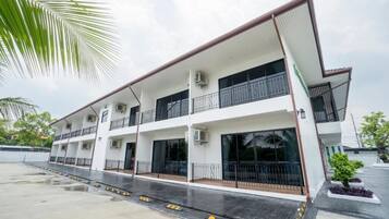 Un edificio de varios pisos con balcones, unidades de aire acondicionado y una entrada con portón.