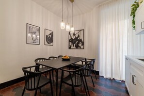 Un comedor con una mesa rectangular, sillas negras y tres lámparas colgantes.