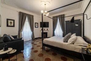 Un dormitorio moderno con cama, sofá, televisión y chimenea.