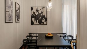 A dining area with a long table, black chairs, and a fruit bowl. There are abstract paintings on the wall and a pendant light above the table. - Casa Dolce Roma – Your home in the heart of Rome! (Roma)