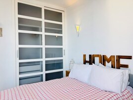 Ein Schlafzimmer mit einem Bett, einem Kleiderschrank und einer Wandleuchte.