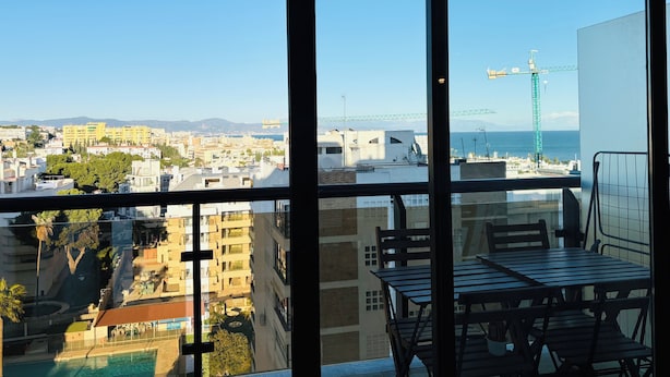 Un balcón con vista a un paisaje urbano, que incluye edificios y un puente distante.
