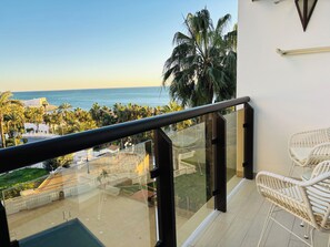 A balcony with a glass railing overlooking a pool and a view of the ocean. - Benalmádena Mood Torremar Beach & Marina (Benalmádena)