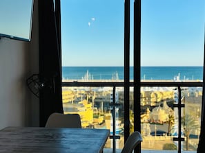 Um quarto com vista para o mar, uma mesa e uma cadeira.
