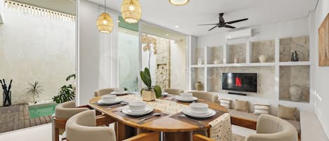 Un espace repas moderne avec une table en bois, des assiettes blanches et des chaises de couleur beige.