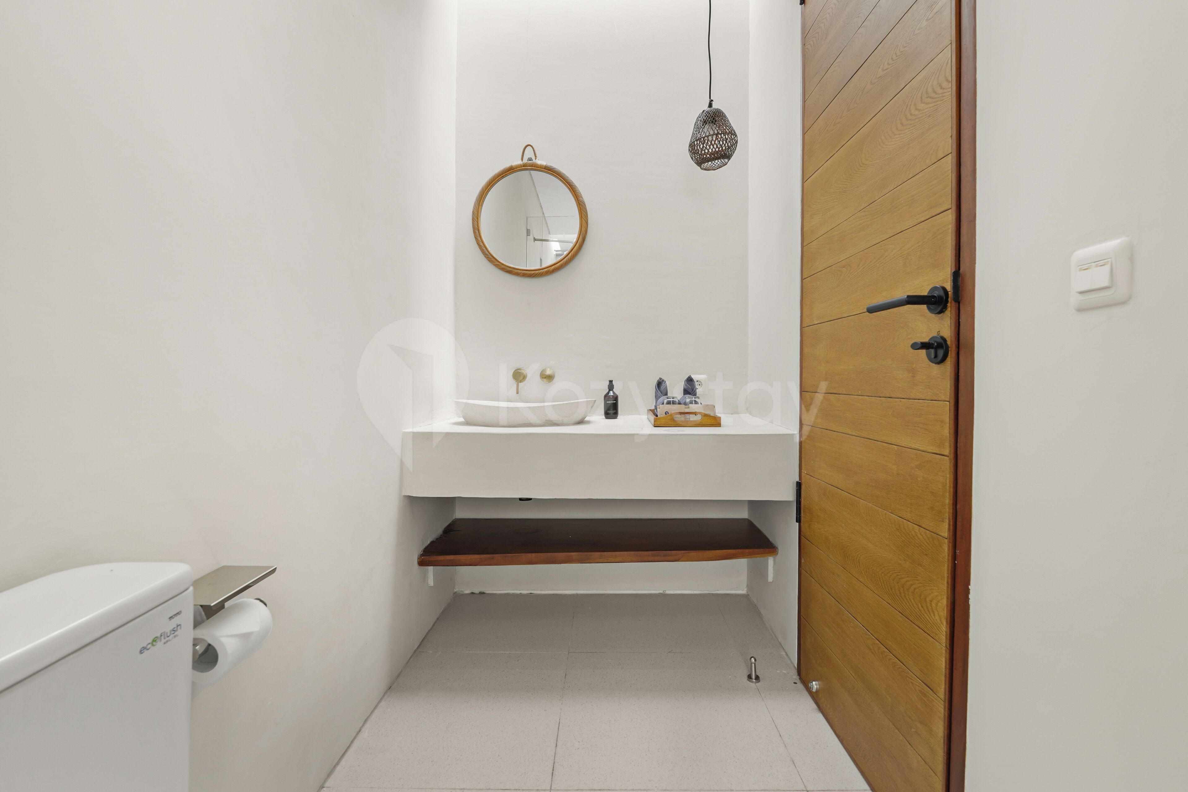 A compact bathroom with a white sink, a round mirror, and a hanging light fixture.