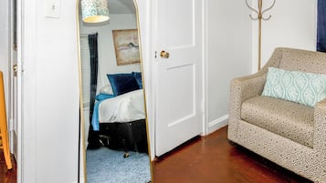 Une pièce avec un lit, un canapé, un miroir et une porte.