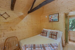 Une pièce dans un chalet en bois, comprenant un lit, une chaise et une fenêtre.
