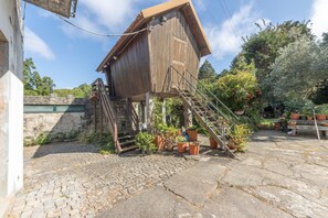 A wooden structure with a staircase leading to a platform, surrounded by potted plants and a cobblestone ground.