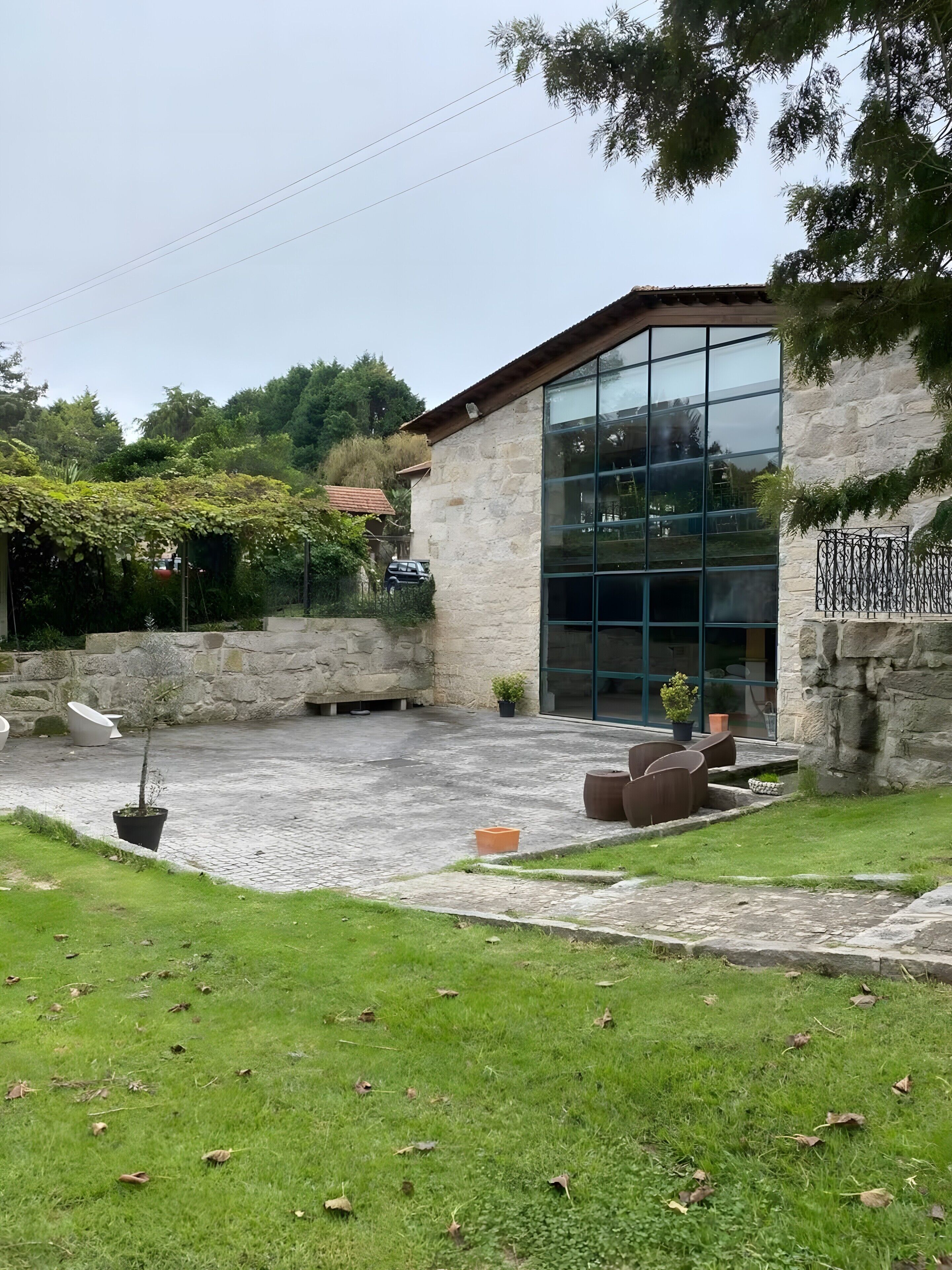 A stone building with a glass facade, a paved courtyard, and outdoor seating.