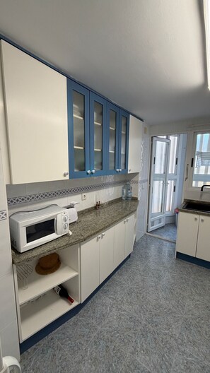 A kitchen with white cabinets, a microwave, and a water dispenser.
