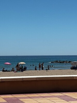 A beach with people, umbrellas, and a rocky shoreline. - Beachfront apartment with private terrace, pool and parking (El Campello)