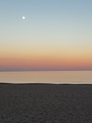 Ein Strand mit blauem Himmel und einem sichtbaren Mond.