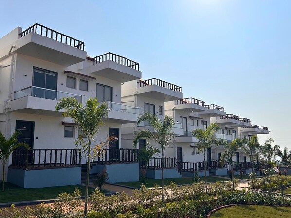 A modern multi-story residential building with balconies and a well-maintained garden.