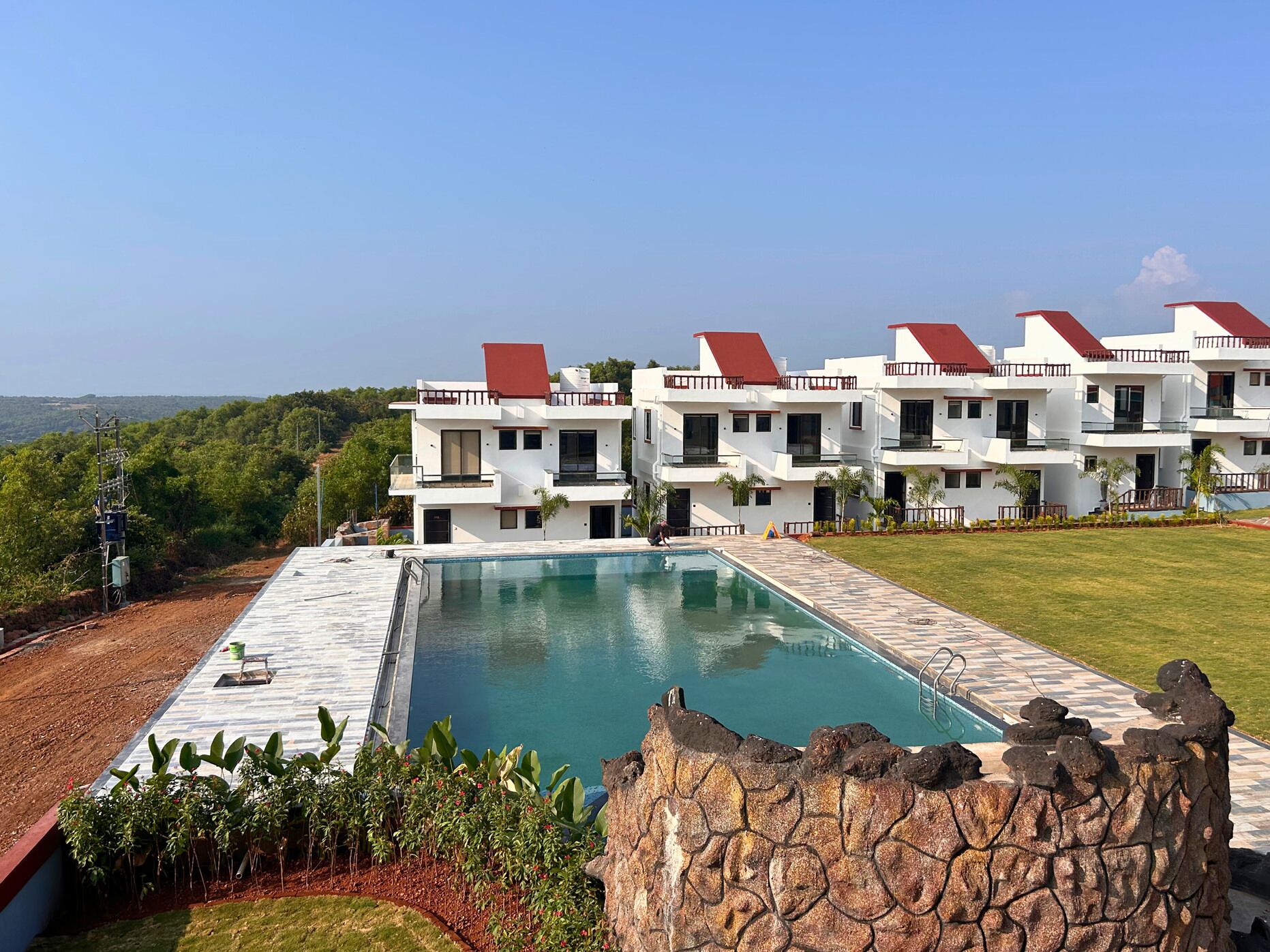 A modern hotel with a swimming pool, multiple balconies, and a view of the surrounding landscape.