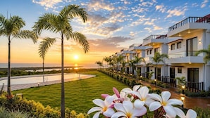 Un resort con piscina, palmeras y vista al atardecer.
