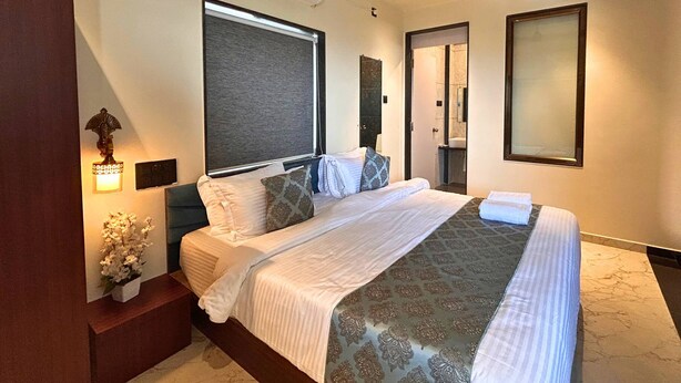 Habitación de hotel con cama, mesitas de noche, aire acondicionado montado en la pared y ventana con vistas.