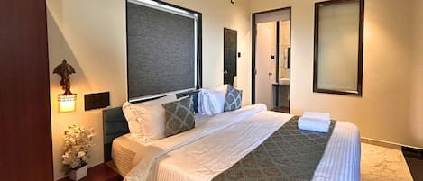 A hotel room with a bed, bedside tables, a wall-mounted air conditioner, and a window with a view.