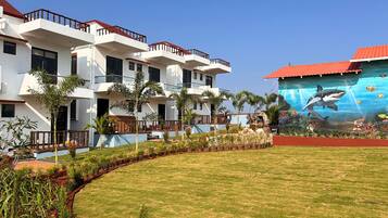 A modern hotel with multiple balconies, a well-maintained lawn, and an underwater mural on the side.