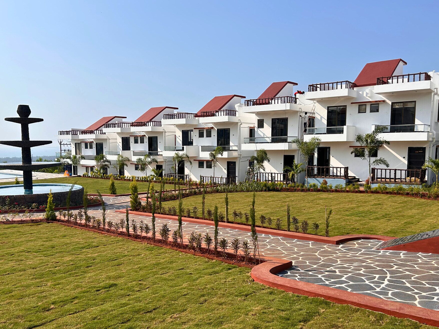 A multi-story hotel with a modern architectural design, featuring balconies and a landscaped garden area.
