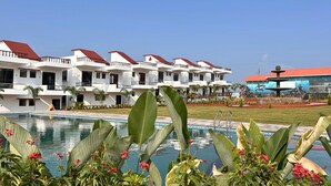 Un hotel con varias construcciones blancas, una piscina y jardines tropicales.