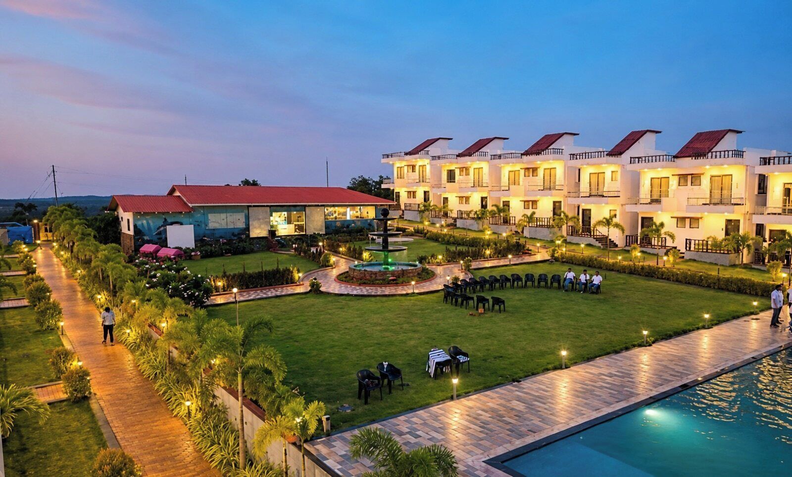 A hotel with multiple buildings, a swimming pool, and a well-maintained garden.