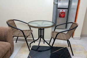A small outdoor seating area with a glass-top table and wicker chairs. - Affordable 1 Bedroom Apartment in Utawala Nairobi Near JKIA (Nairobi)
