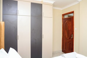 Ein Zimmer mit Schrank, Holztür und weißem Bett.