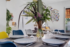 A dining table set with plates, cutlery, and a vase with flowers. - Villa "Upper" – 3 bedrooms, 8 guests, private terrace, Wi-Fi, air conditioning (Cagnes-sur-Mer)