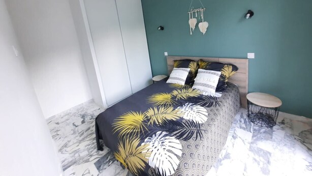 Ein Schlafzimmer mit einem Bett, Nachttischen, einer Hängelampe und einem Kleiderschrank.