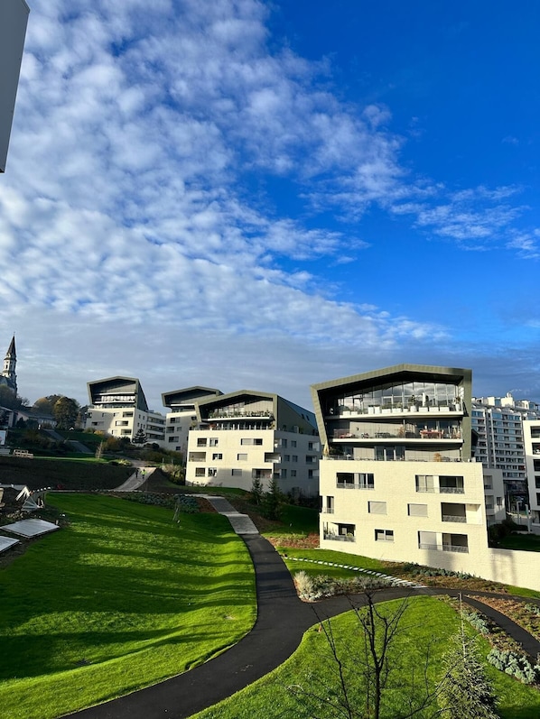 Un moderno complejo de apartamentos con varios edificios, césped bien cuidado y cielo despejado.