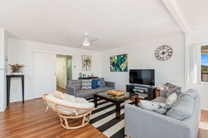 A living room with a sofa, armchair, coffee table, television, and a ceiling fan. - Ideal for Tradies. BBQ, WiFi, Pet friendly (Torquay)